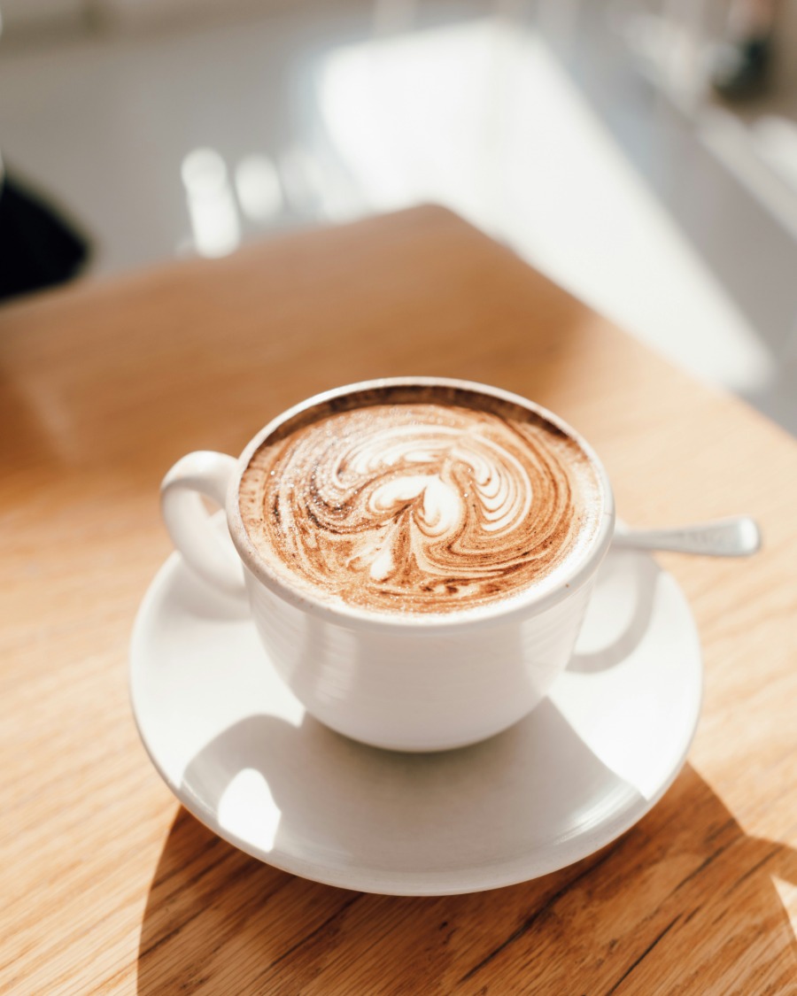A flat white being poured in a ceramic cup.